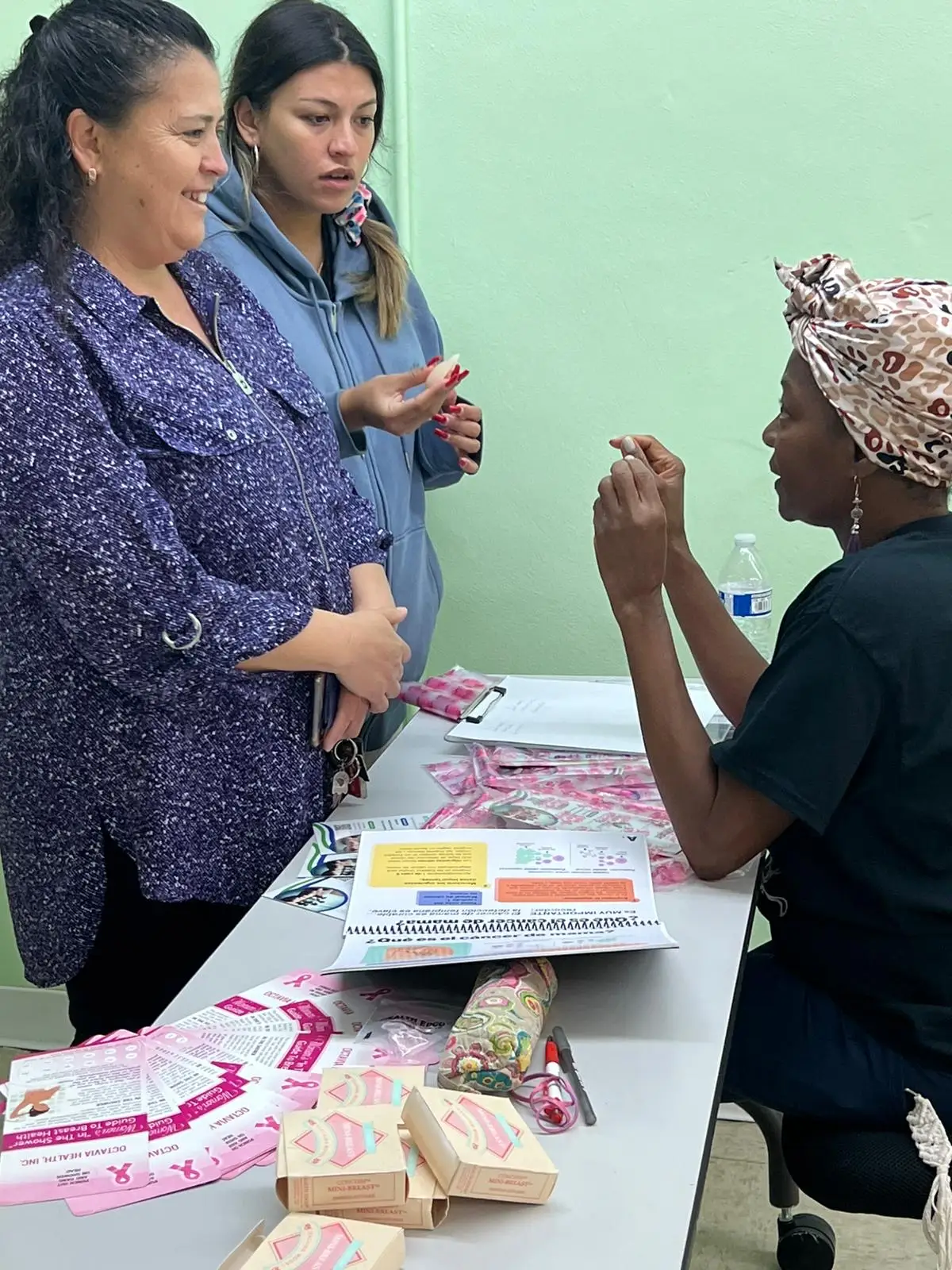 An Octavia Health educator showing breast self-exam materials to a community member during an outreach session.